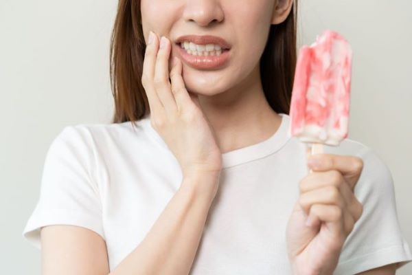 donna con gelato che prova dolore al dente